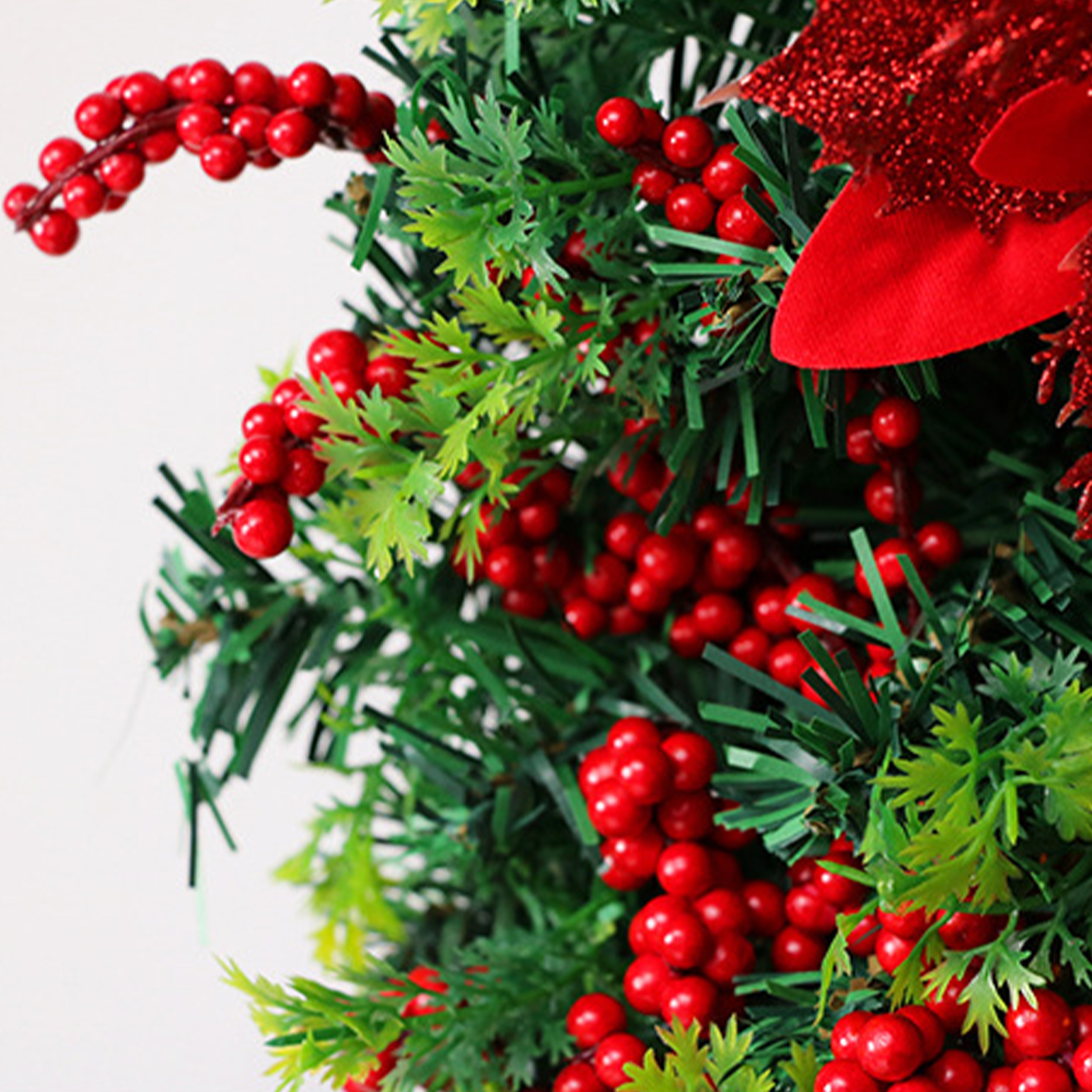 Nahaufnahme einer Weihnachtsdekoration. Mit roten Beeren, grünen Blättern und einer roten Glitzer-Schleife.