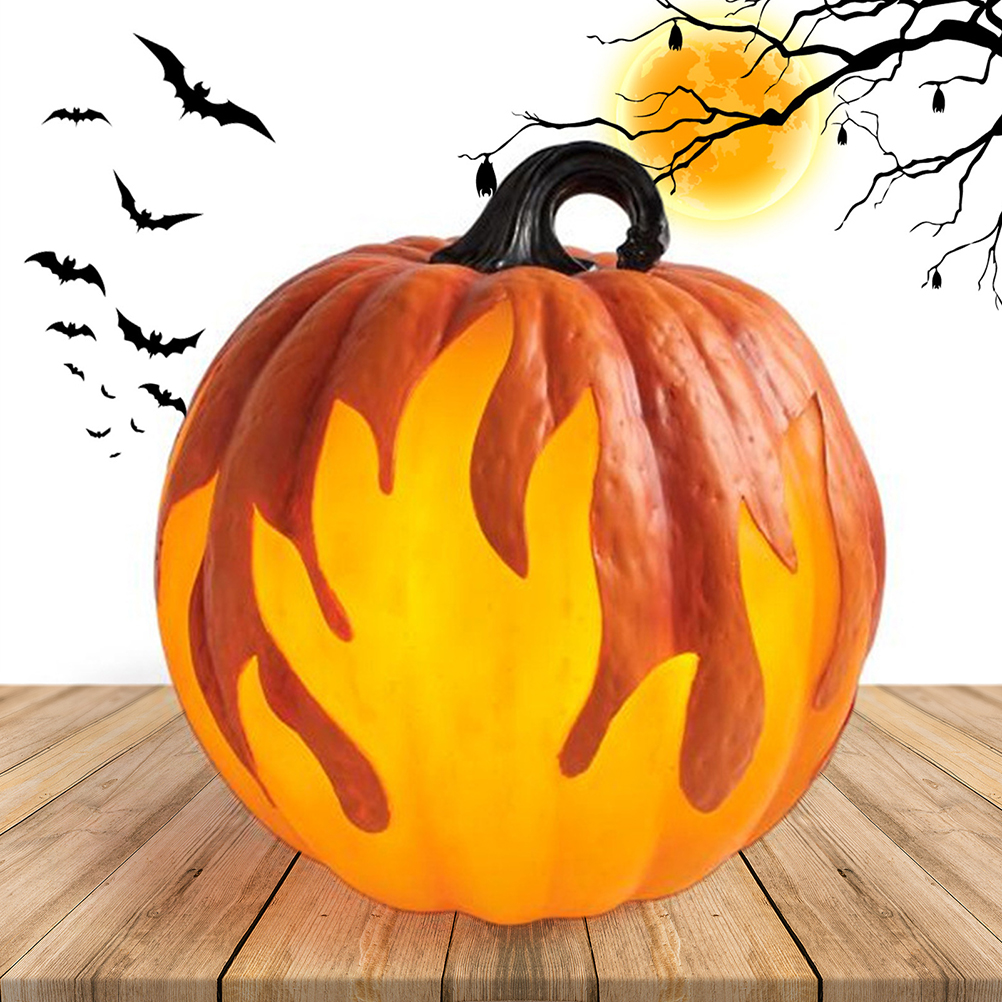 Ein beleuchteter Halloween-Kürbis mit flammenartigen Ausschnitten. Fledermäuse fliegen herum. Im Hintergrund sind Mond und Äste. Er steht auf Holz.