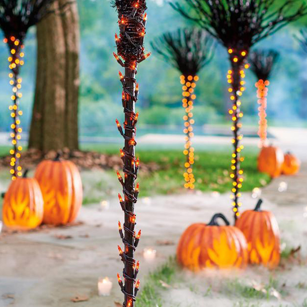 Halloween-Szene mit Kürbissen, dekorativen Lichtern an Stangen und Nebel. Orangefarbene Kürbisse und Lichter schaffen Feststimmung.
