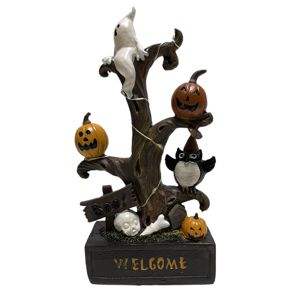 Eine Halloween-Dekoration mit einem Baum, Kürbissen, einem Geist, einer Eule und einem Schädel. Auf dem Sockel steht 'WELCOME'.