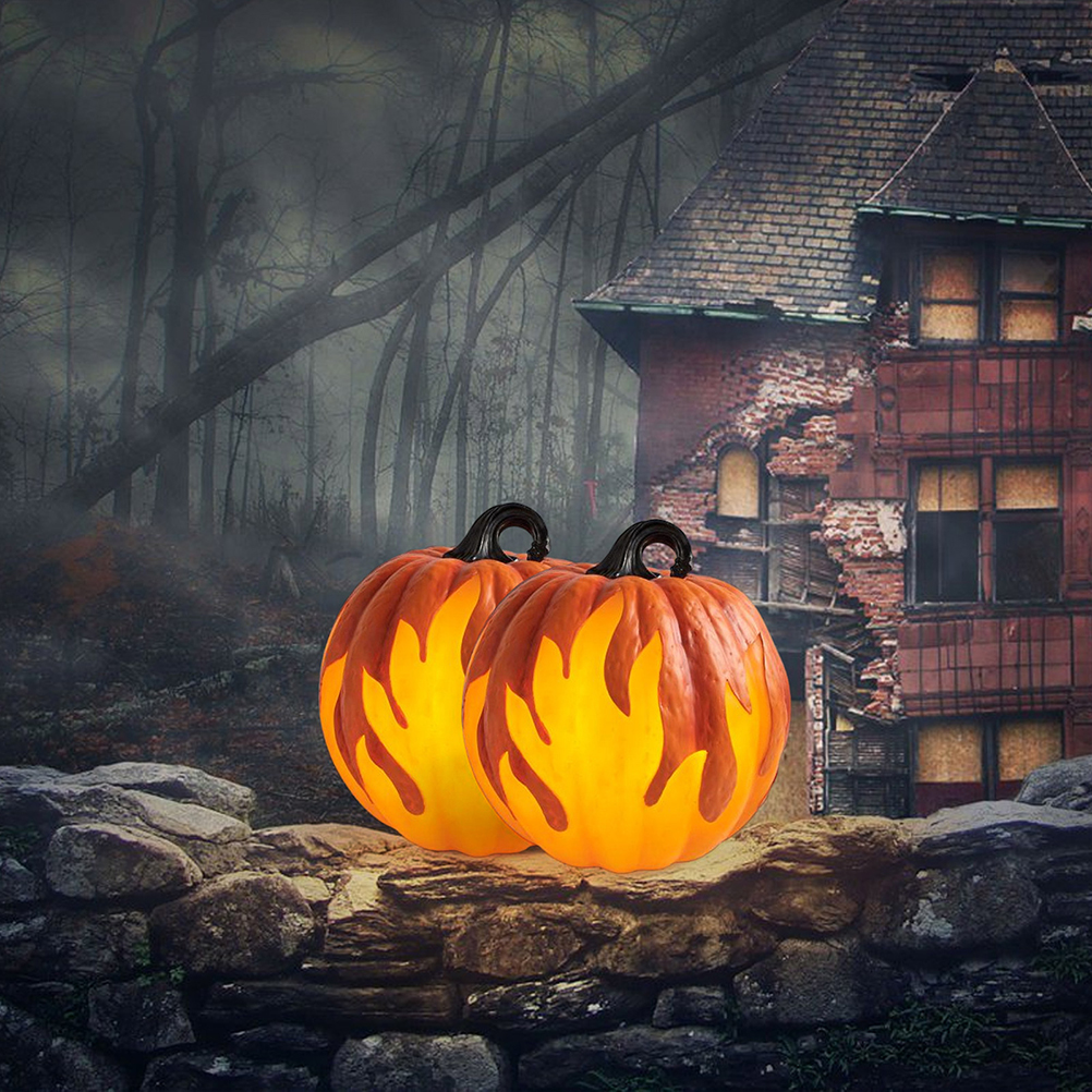 Zwei beleuchtete Halloween-Kürbisse auf einer Steinmauer, mit einem gruseligen Haus und Wald im Hintergrund.