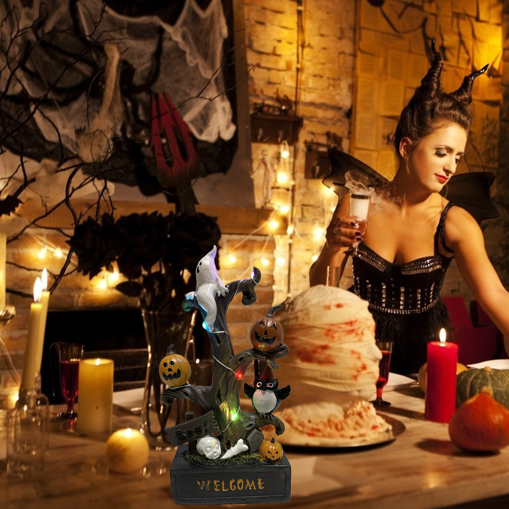 Halloween-Szene: Frau mit Hörnern, Tisch mit Dekorationen und Willkommensschild, dekorativer Baum mit Kürbissen und Geist.