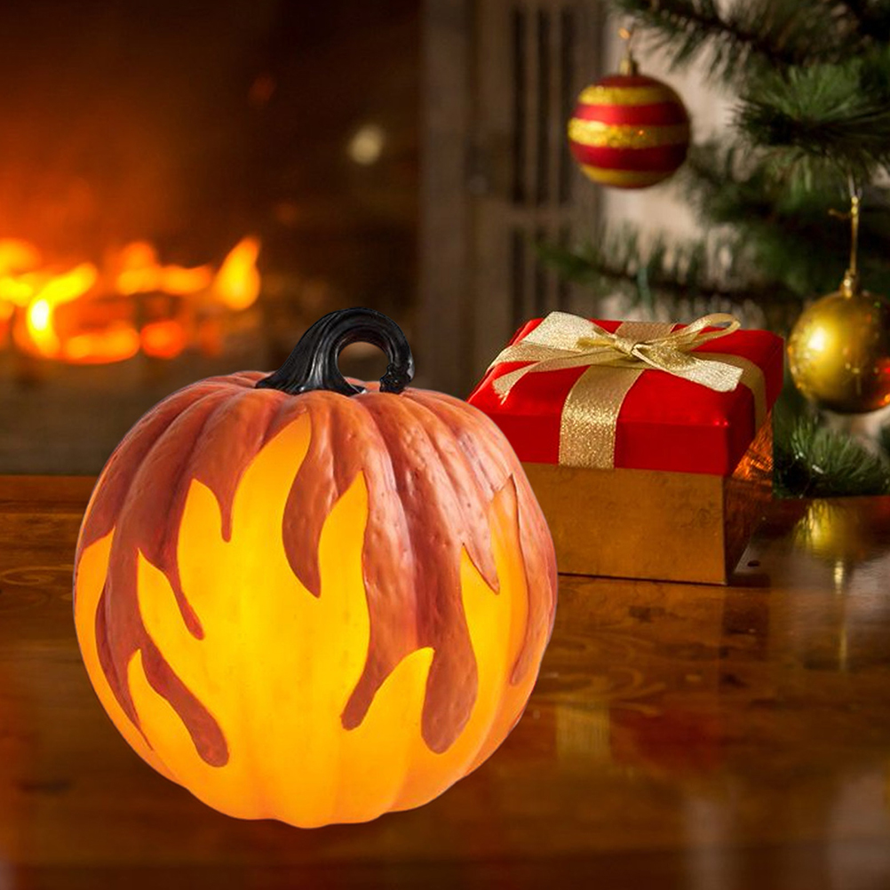 Ein leuchtender Kürbis mit Flammenausschnitten. Eine rote Geschenkbox mit goldener Schleife und Weihnachtsbaumschmuck im Hintergrund.