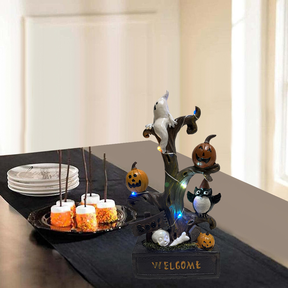 Halloween-Dekoration: Baum mit Geist, Kürbissen, Eule und Willkommensschild. Marshmallows an Stöcken und Teller auf dem Tisch.