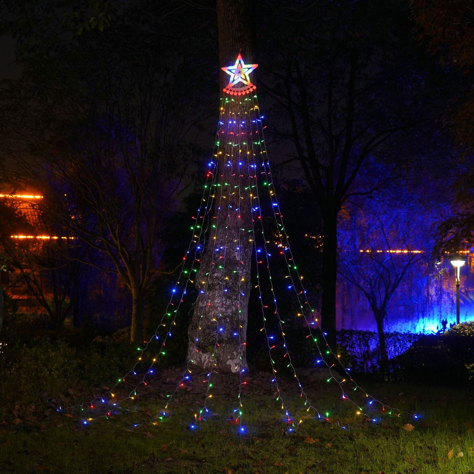 Ein Baum, der mit kaskadierenden bunten Lichtern geschmückt ist und eine Weihnachtsbaumform bildet, gekrönt von einem Stern. Nachtszene.