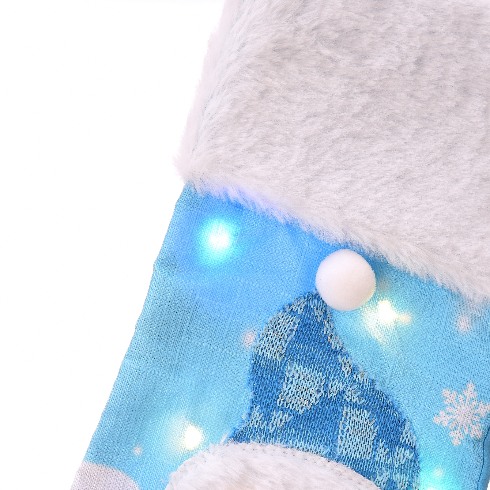Nahaufnahme eines Weihnachtsstrumpfes. Blauer Stoff mit weißem Besatz und einem weißen Pompon. Beleuchtet mit blauen Lichtern und Schneeflockenmuster.
