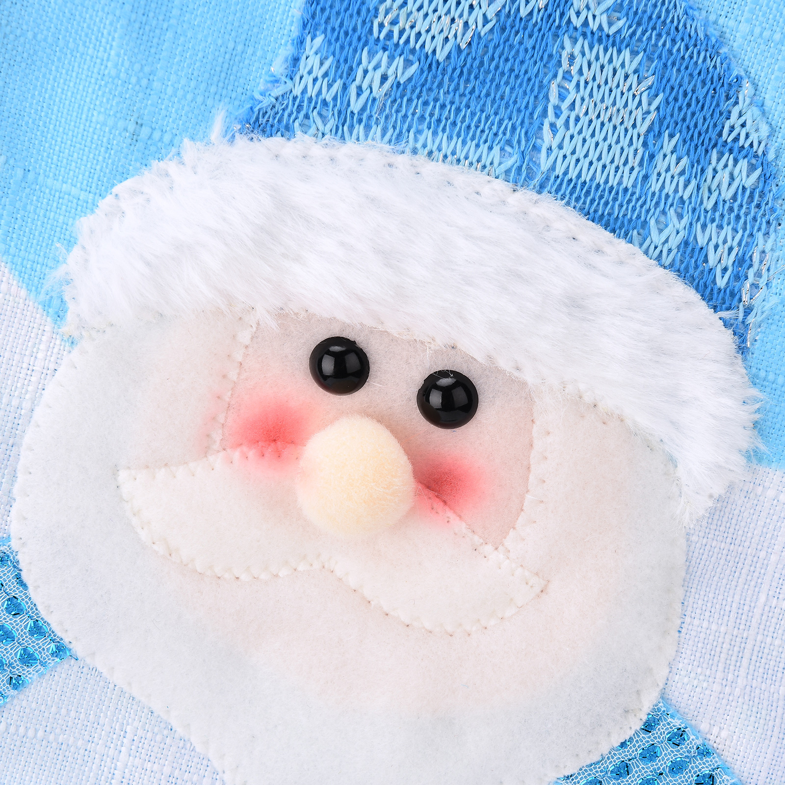 Nahaufnahme einer Santa-Gesichtsdekoration. Es hat schwarze Augen, rosa Wangen, eine beige Nase und einen weißen Bart auf blauem Hintergrund.