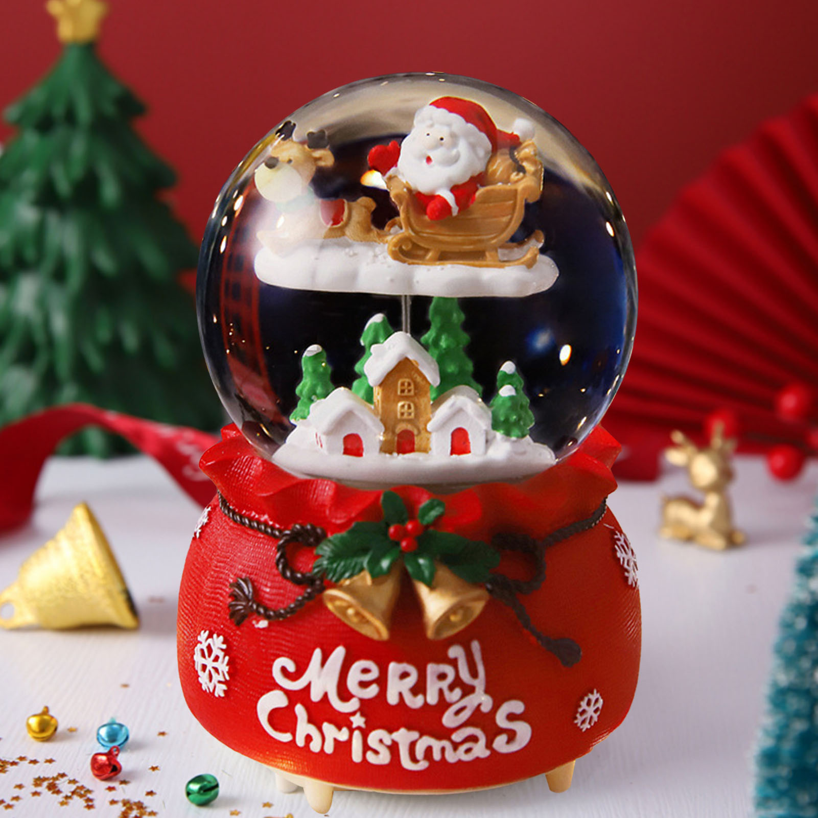 Eine Schneekugel mit Weihnachtsmann und Rentier. Sie steht auf einem roten Sockel mit der Aufschrift Frohe Weihnachten. Weihnachtsbäume sind im Hintergrund.