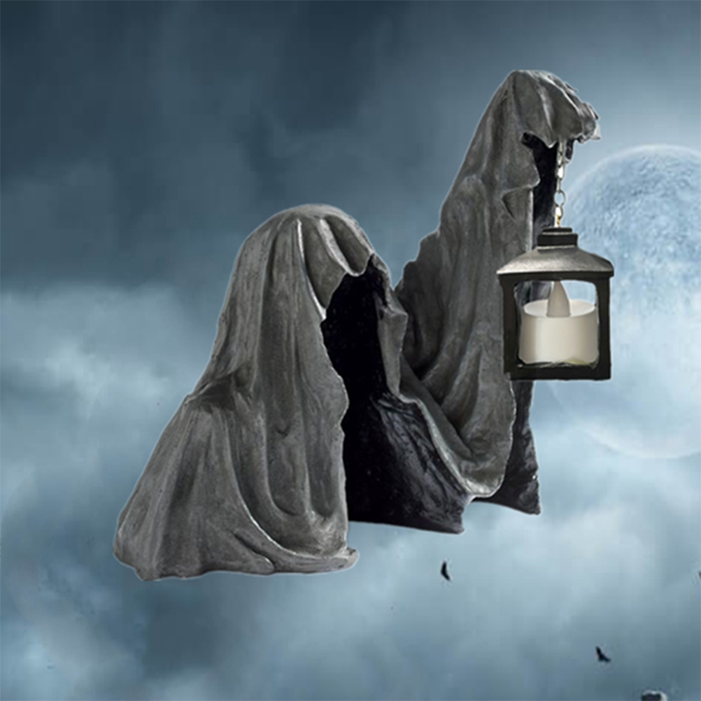 Eine Halloween-Dekoration einer vermummten Figur mit einer hängenden Laterne. Grauer Umhang mit dunklem Innenraum. Der Hintergrund hat einen Mond und einen dunklen Himmel.