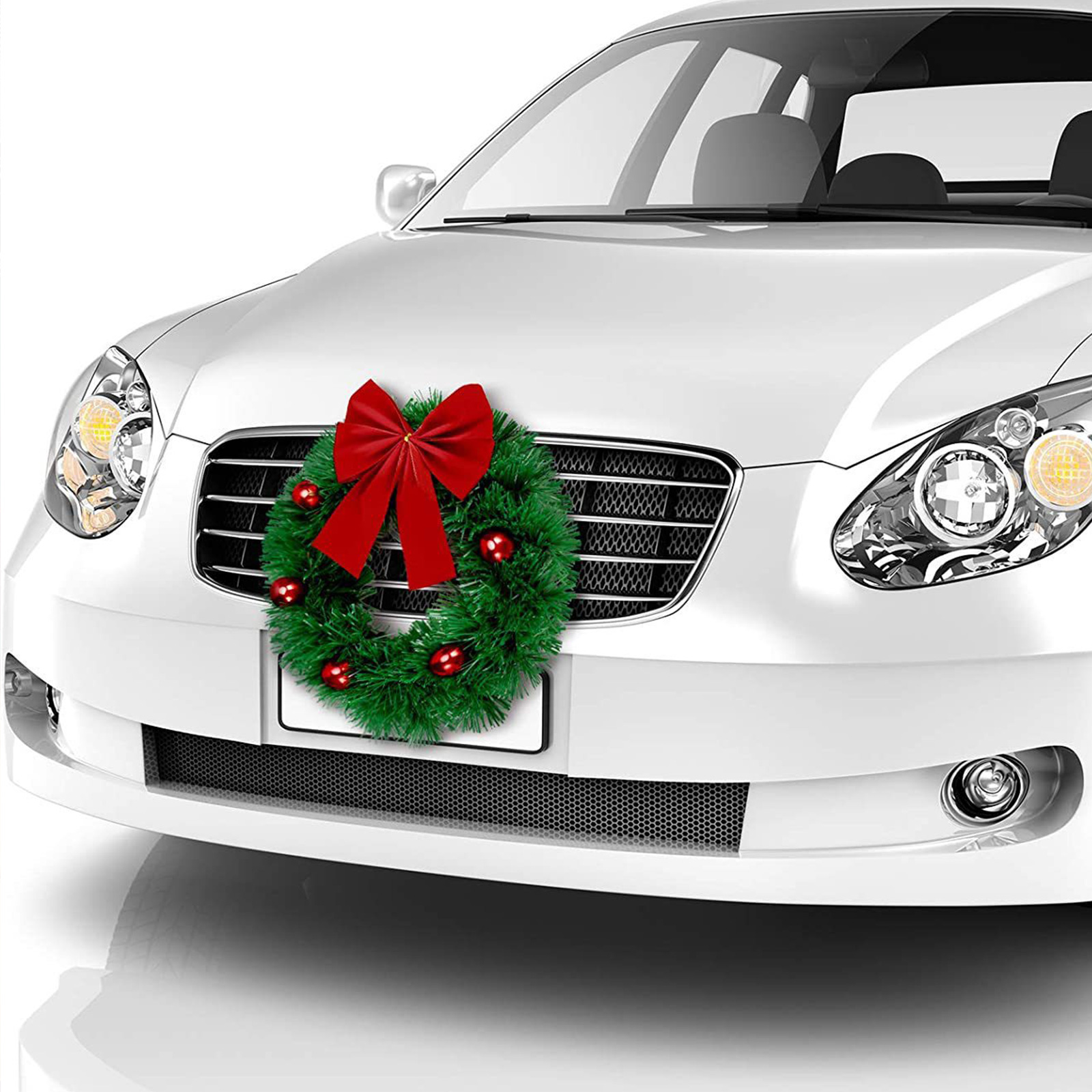 Weißes Auto mit Weihnachtskranz. Der Kranz ist grün mit roten Ornamenten und einer großen roten Schleife.