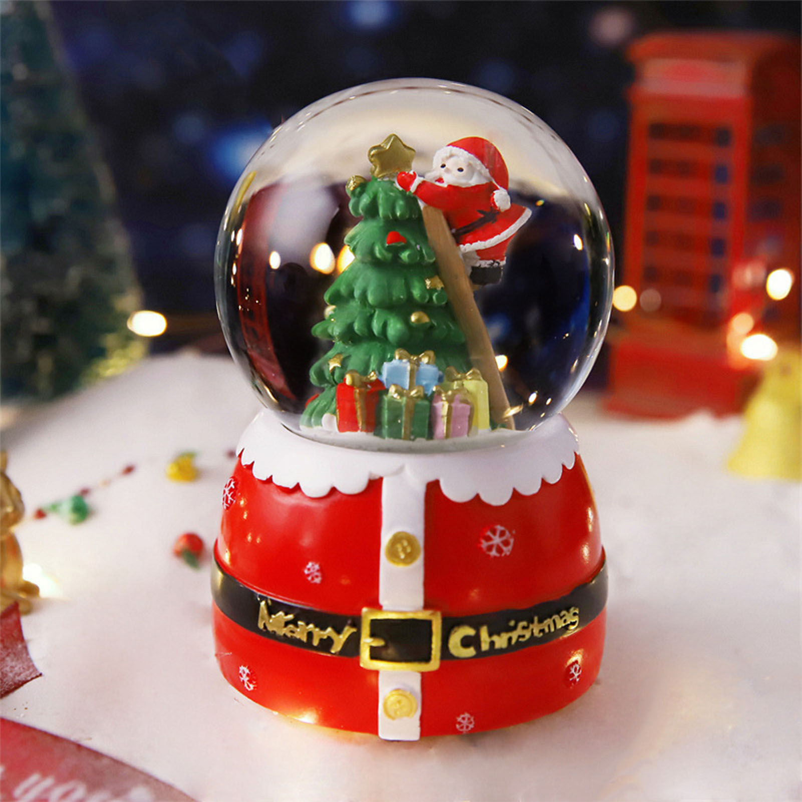 Eine Weihnachtskugel mit Weihnachtsmann, Weihnachtsbaum und Geschenken. Der Sockel ist rot mit der Aufschrift 'Merry Christmas'.