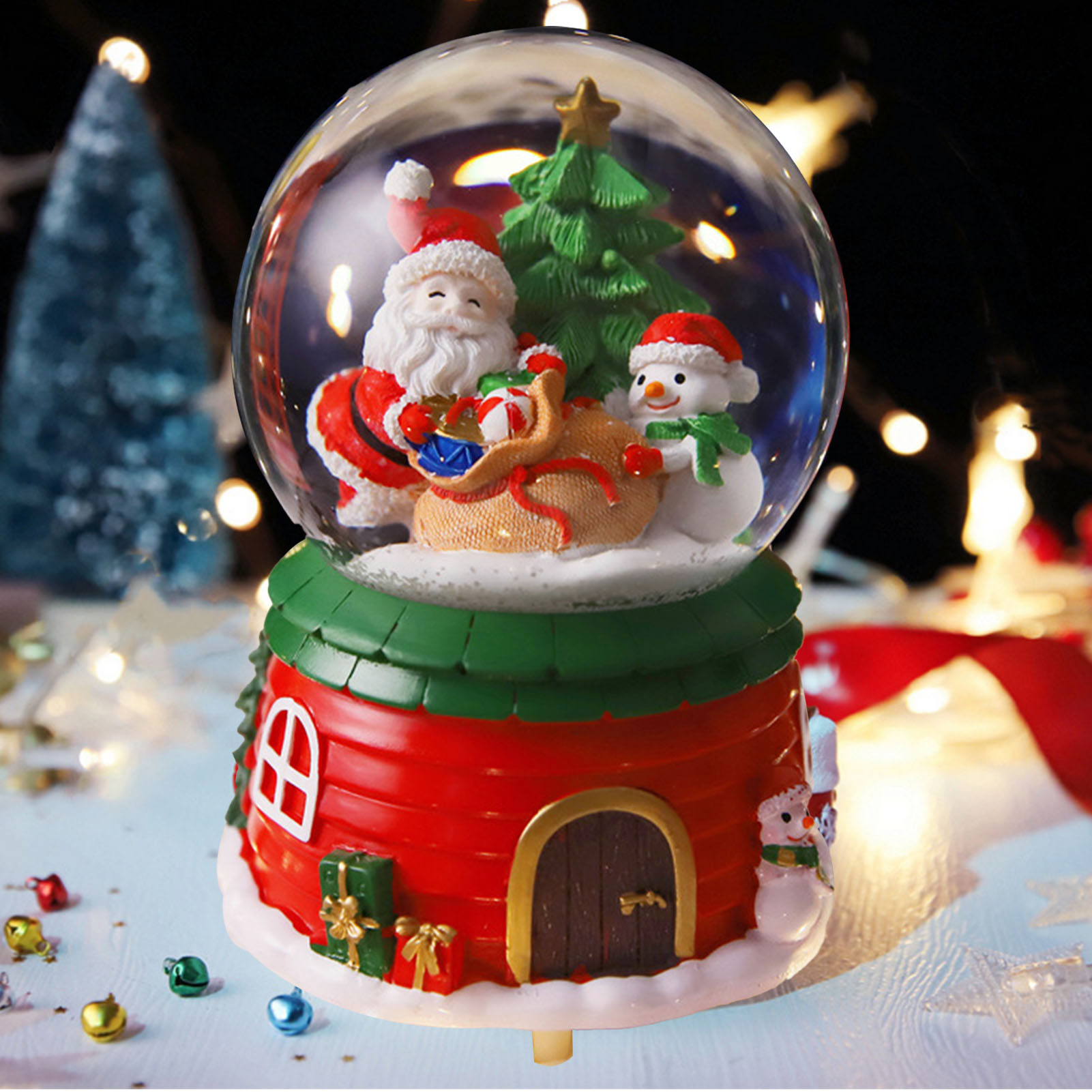 Eine Weihnachtsschneekugel mit Weihnachtsmann, Schneemann und Weihnachtsbaum in einem rot-grünen Haus.