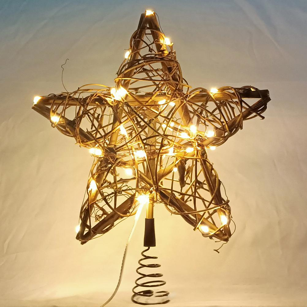 Ein sternförmiger Weihnachtsbaumschmuck aus geflochtenen braunen Ästen, beleuchtet von vielen kleinen Lichtern. Ein schwarzer Metallständer trägt ihn.
