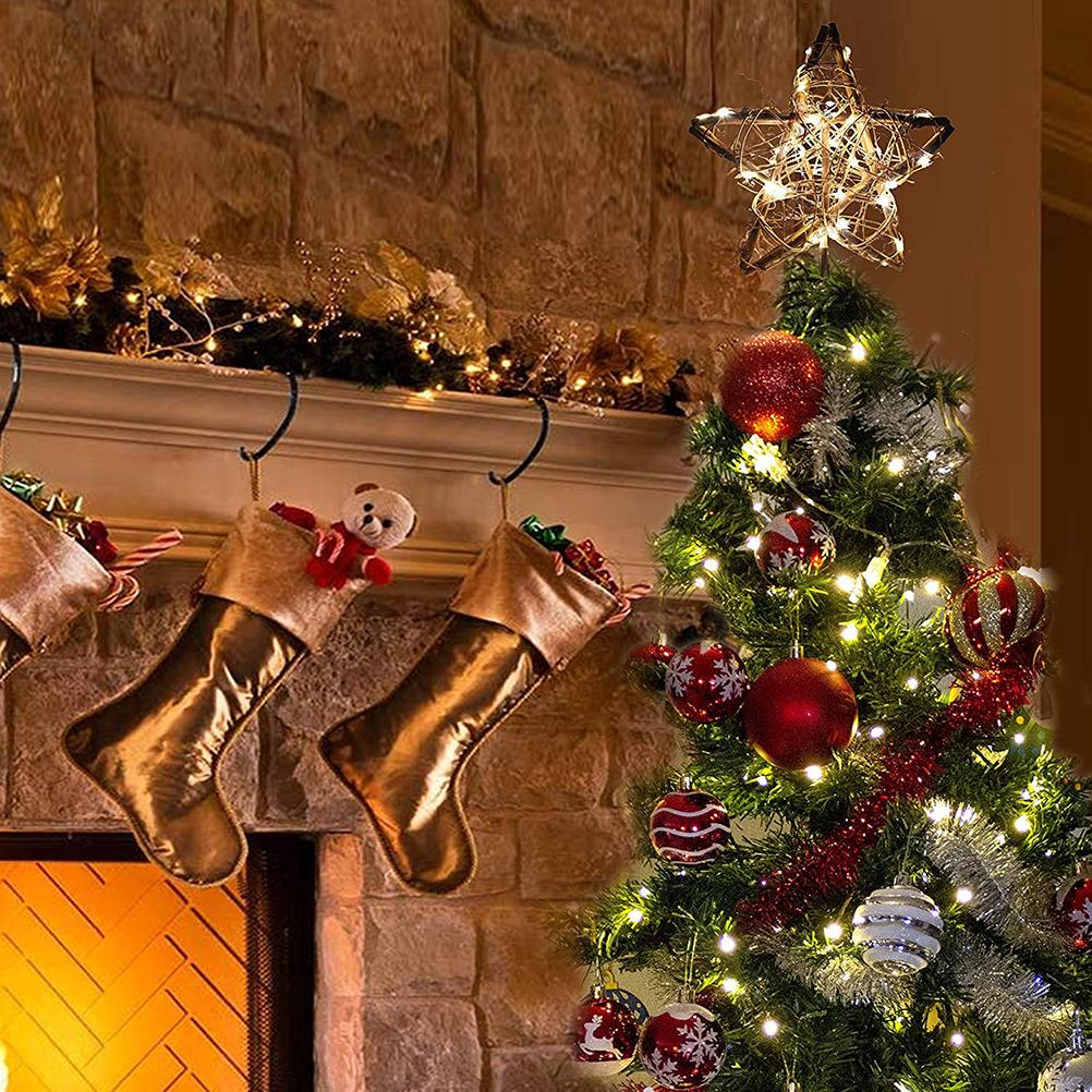 Ein geschmückter Weihnachtsbaum mit Ornamenten und Lichtern. Goldene Strümpfe hängen am Kamin. Ein Stern sitzt auf dem Baum.