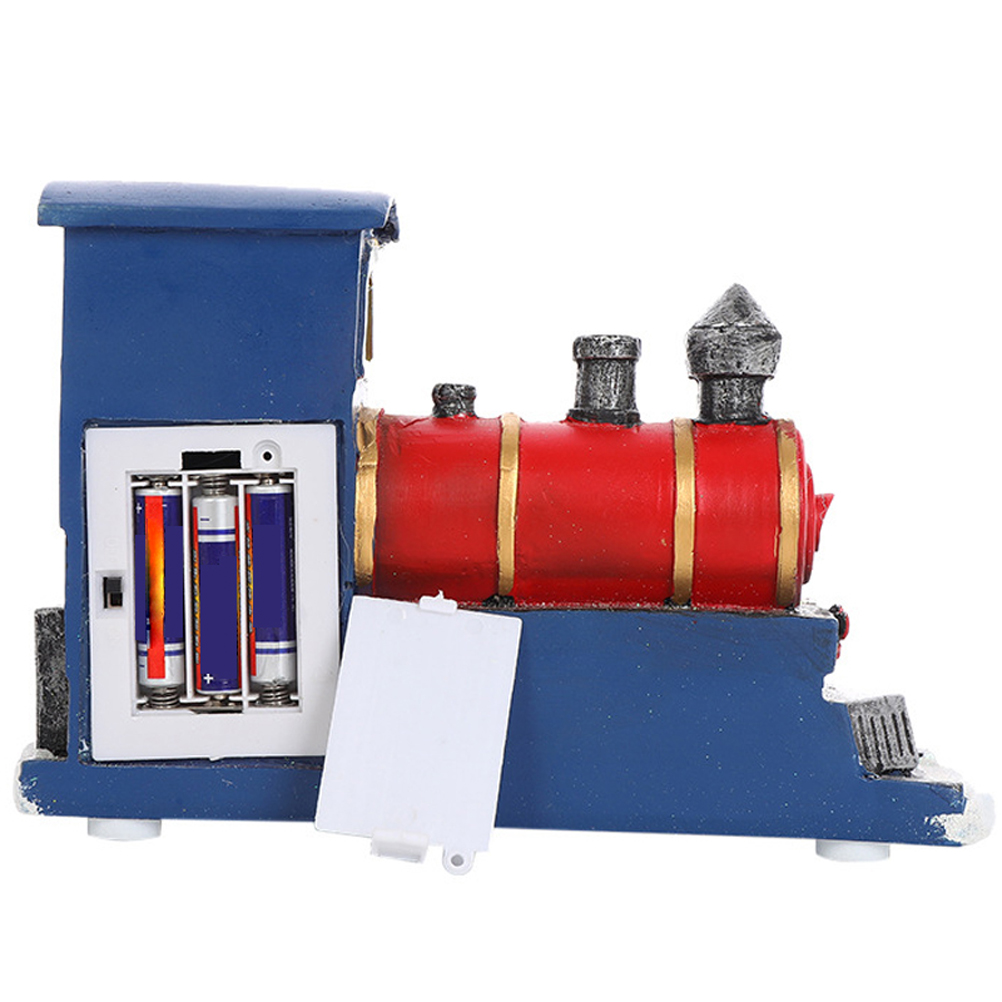 Ein Spielzeugzug mit blauen und roten Farben. Das Batteriefach ist geöffnet und gibt Batterien frei. Der Zug hat einen Schornstein und Räder.