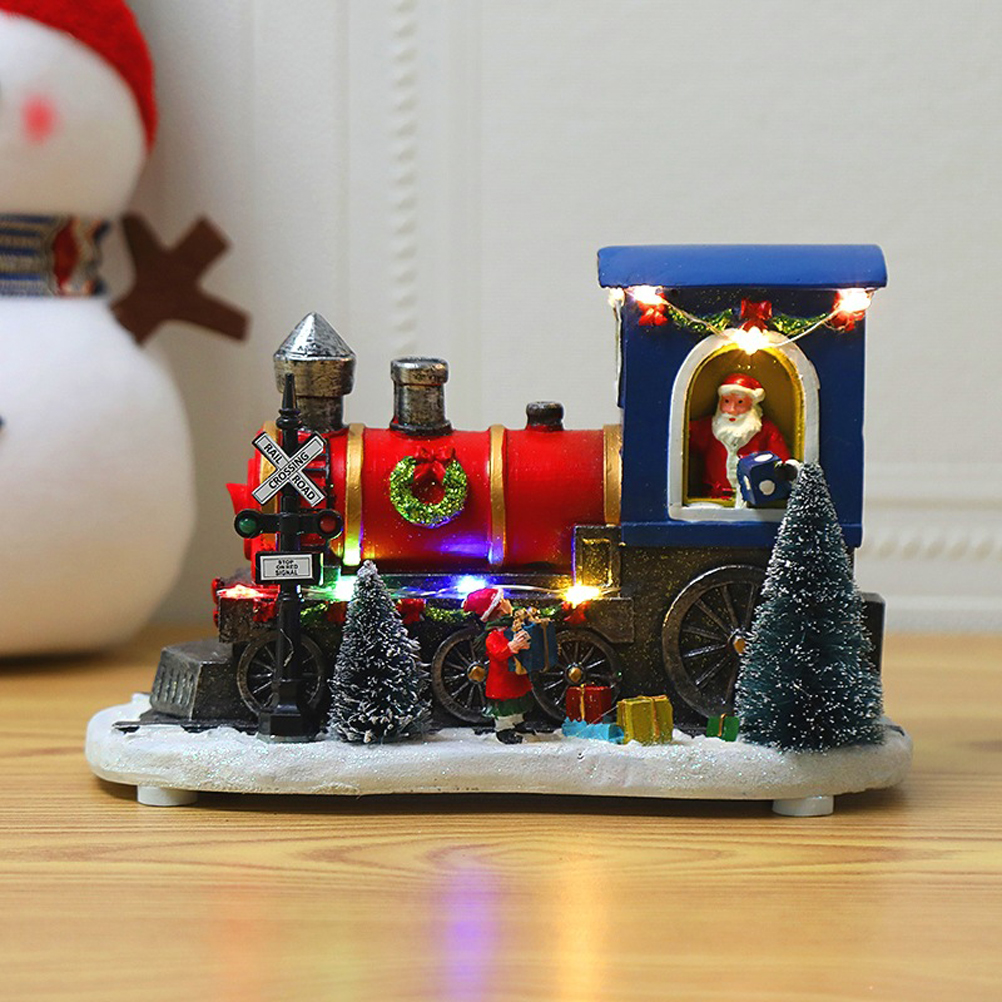Eine festliche Zugdekoration mit Weihnachtsmann, Weihnachtsbäumen und Geschenken. Sie hat rote, blaue und silberne Farben. Im Hintergrund ist ein Schneemann teilweise sichtbar.