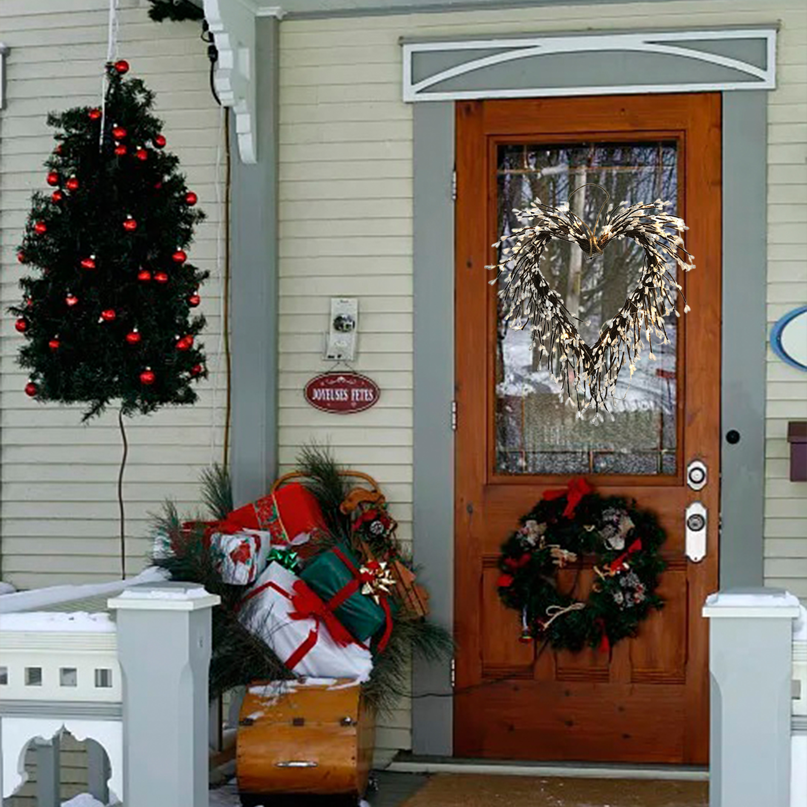 Ein Hauseingang, der für Weihnachten geschmückt ist. Er hat einen herzförmigen Kranz, einen Weihnachtsbaum und Geschenke.