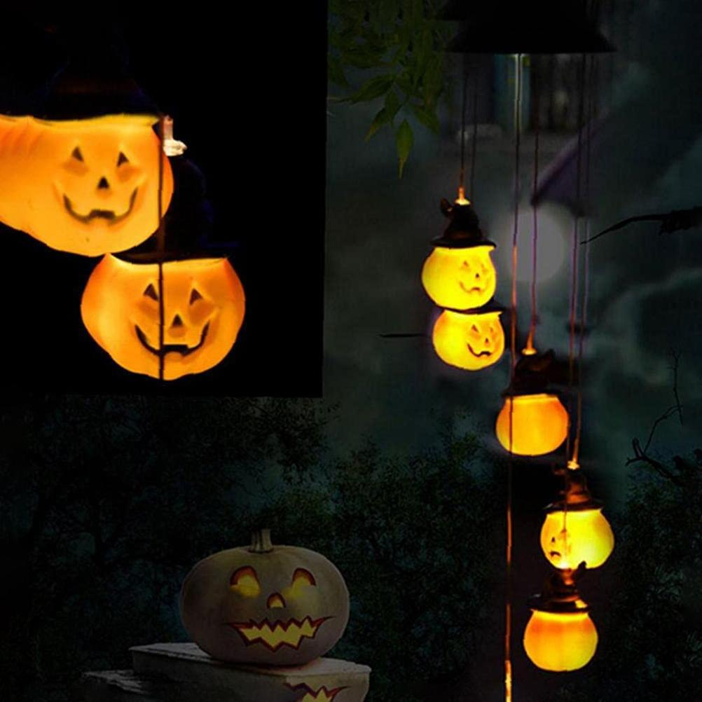 Halloween-Dekorationen: leuchtende Kürbislampen mit Hexenhüten, die an Schnüren hängen. Ein geschnitzter Kürbis steht auf Steinstufen.