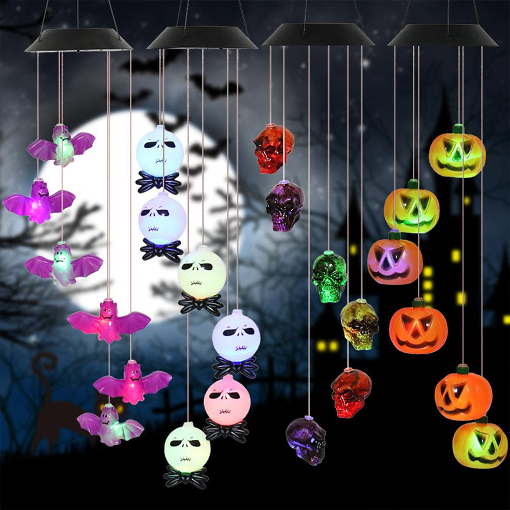 Halloween-Dekorationen: Fledermäuse, Totenköpfe und Kürbisse hängen vor einem mondbeschienenen Himmel. Sie sind in verschiedenen Farben beleuchtet.