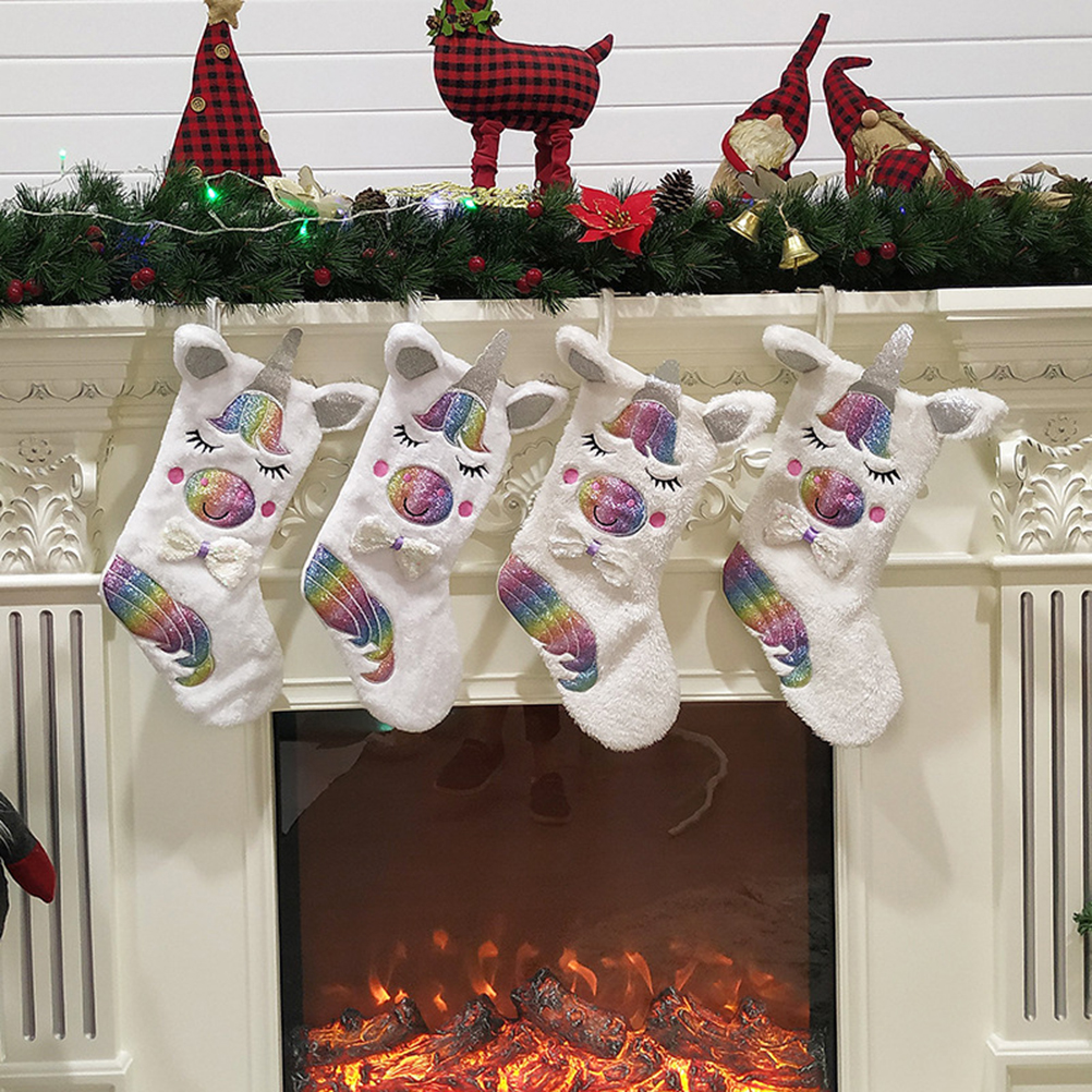 Vier Einhorn-Strümpfe hängen am Kamin. Dekorationen umfassen einen Weihnachtsbaum, ein Rentier, Zwerge und eine Girlande.