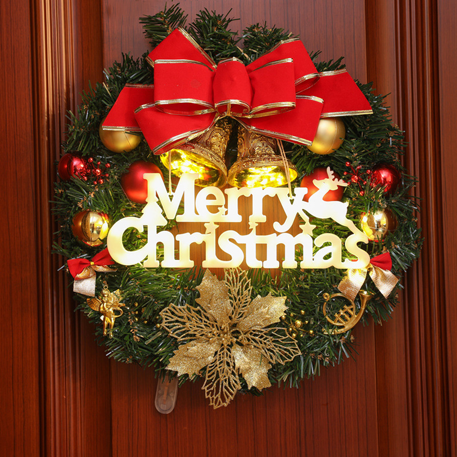 Ein Weihnachtskranz mit roter Schleife, goldenen Glocken und dem Text 'Merry Christmas' auf einer Holztür.