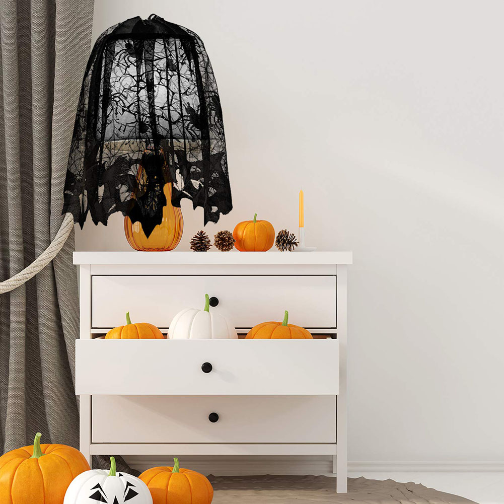 Halloween-Dekoration: Kürbisse, eine schwarze Spitzendecke und eine Kerze auf einer weißen Kommode. Kürbisse auf dem Boden und in den Schubladen.