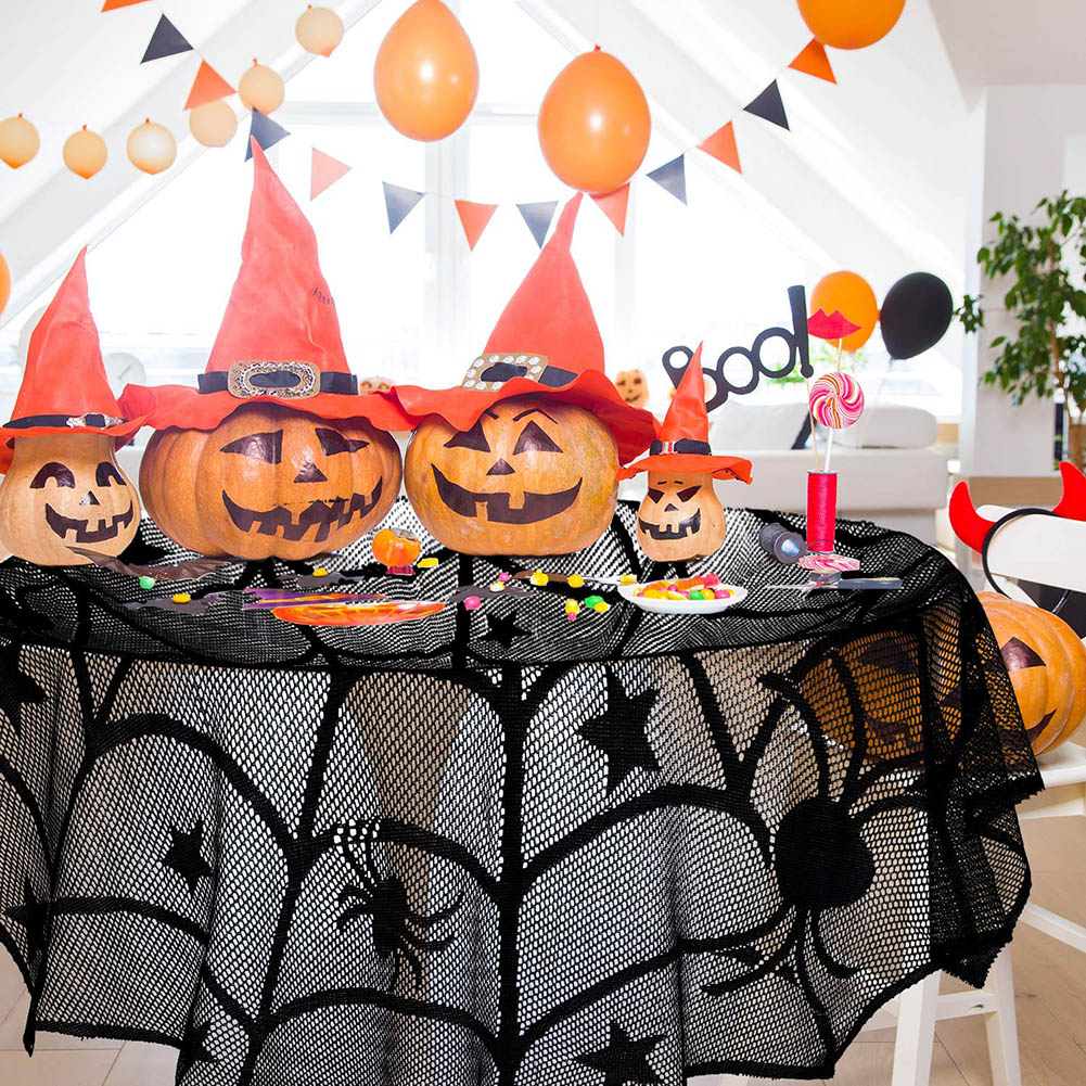 Halloween-Tisch mit Kürbisgesichtern, Hexenhüten, Spinnennetz-Tischdecke, Luftballons und Dekorationen. Orange und Schwarz.
