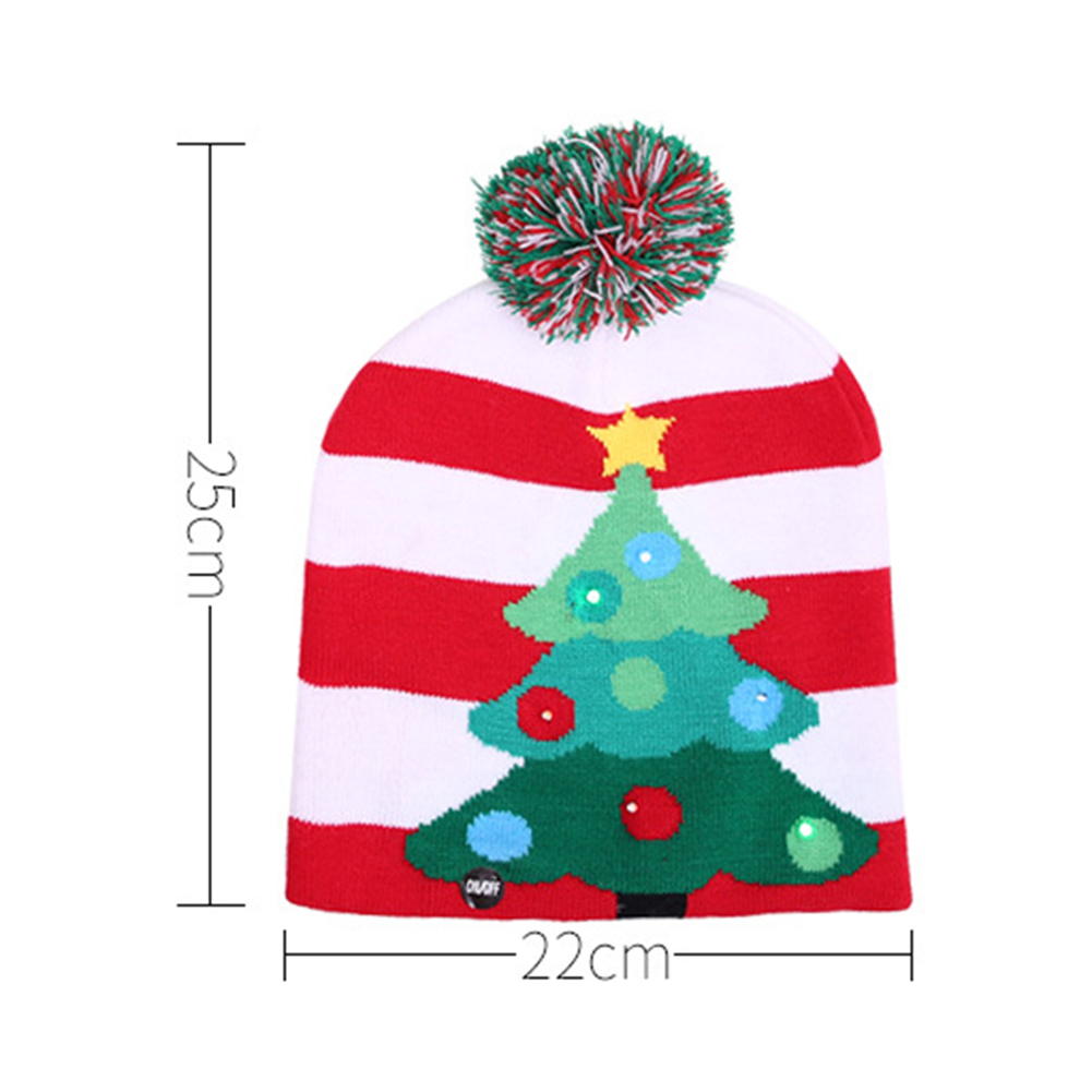 Eine Weihnachtsmütze mit rot-weißen Streifen, einem Bommel und einem grünen Baumdesign mit Lichtern. Maße: 25 cm x 22 cm.