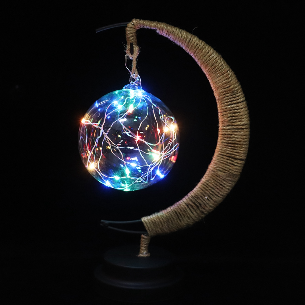 Eine Glaskugel mit bunten Lichtern, die an einem seilbedeckten Ständer vor schwarzem Hintergrund hängt.