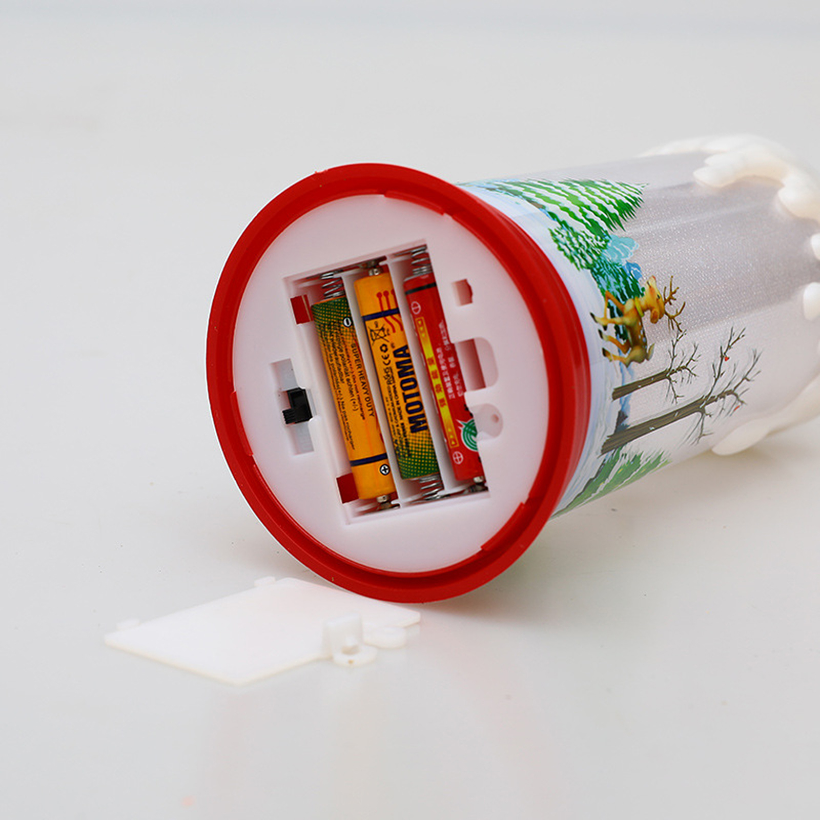 Ein weihnachtlicher Zylinder mit Batterien. Der Zylinder hat einen roten Rand und eine Weihnachtsszene.