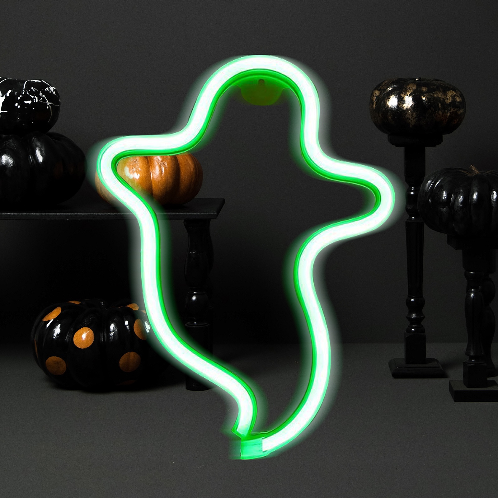 Ein grüner Neon-Geist-Umriss mit Kürbissen, darunter schwarze mit Gold und orangen Punkten, auf dunklem Hintergrund.