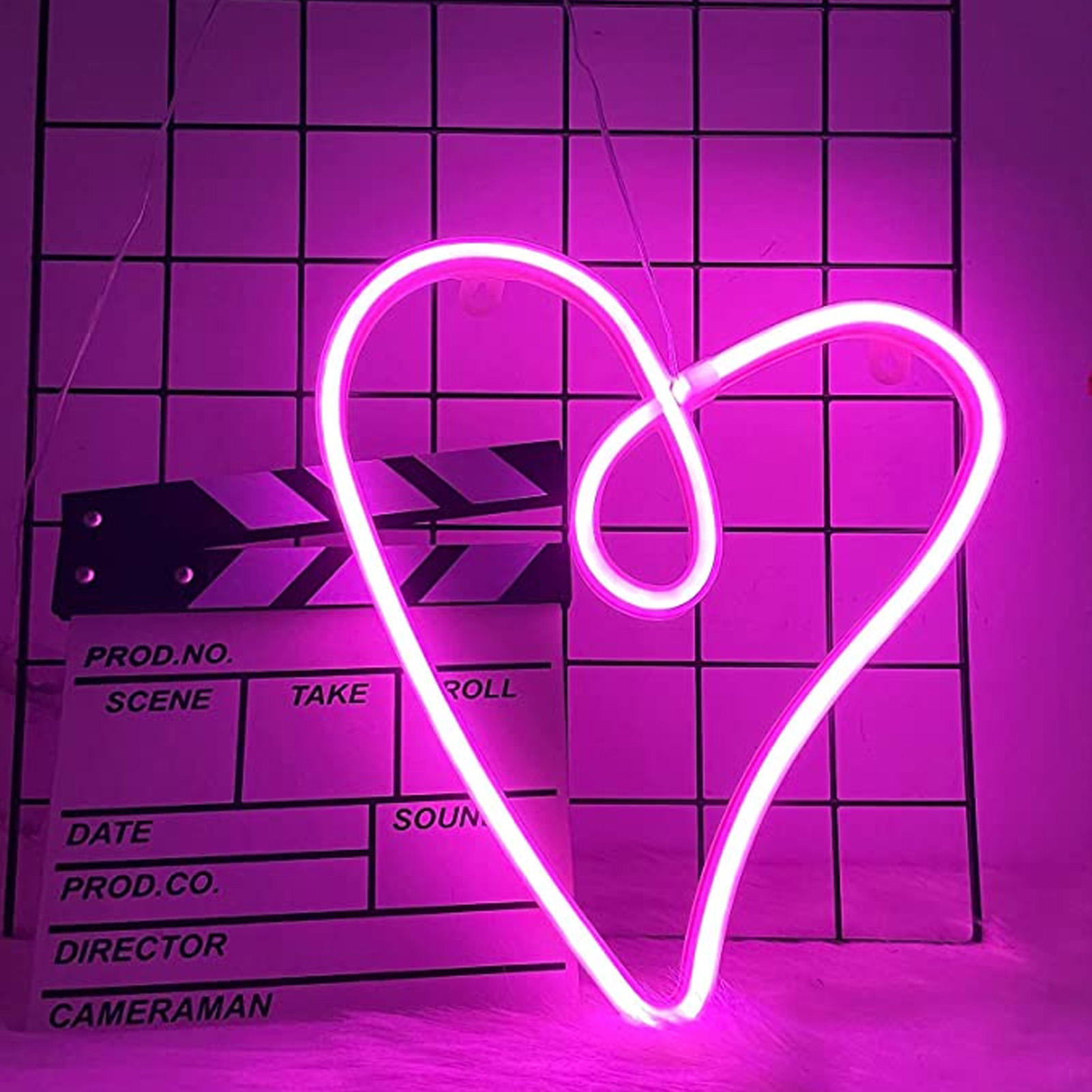 Rosa Neonherz mit einer Filmklappe vor einem quadratischen, gefliesten Hintergrund.