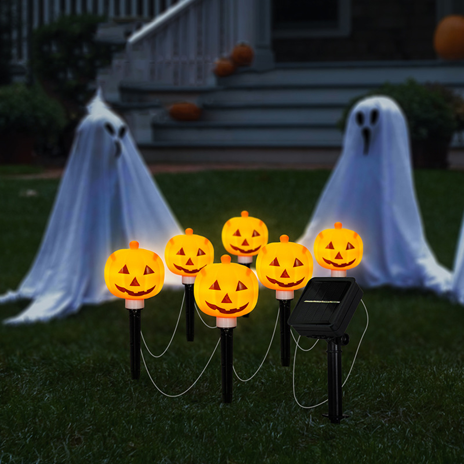 Halloween-Szene mit Kürbislichtern, Geisterdekorationen und einem Haus im Hintergrund. Solarpanel vorhanden.