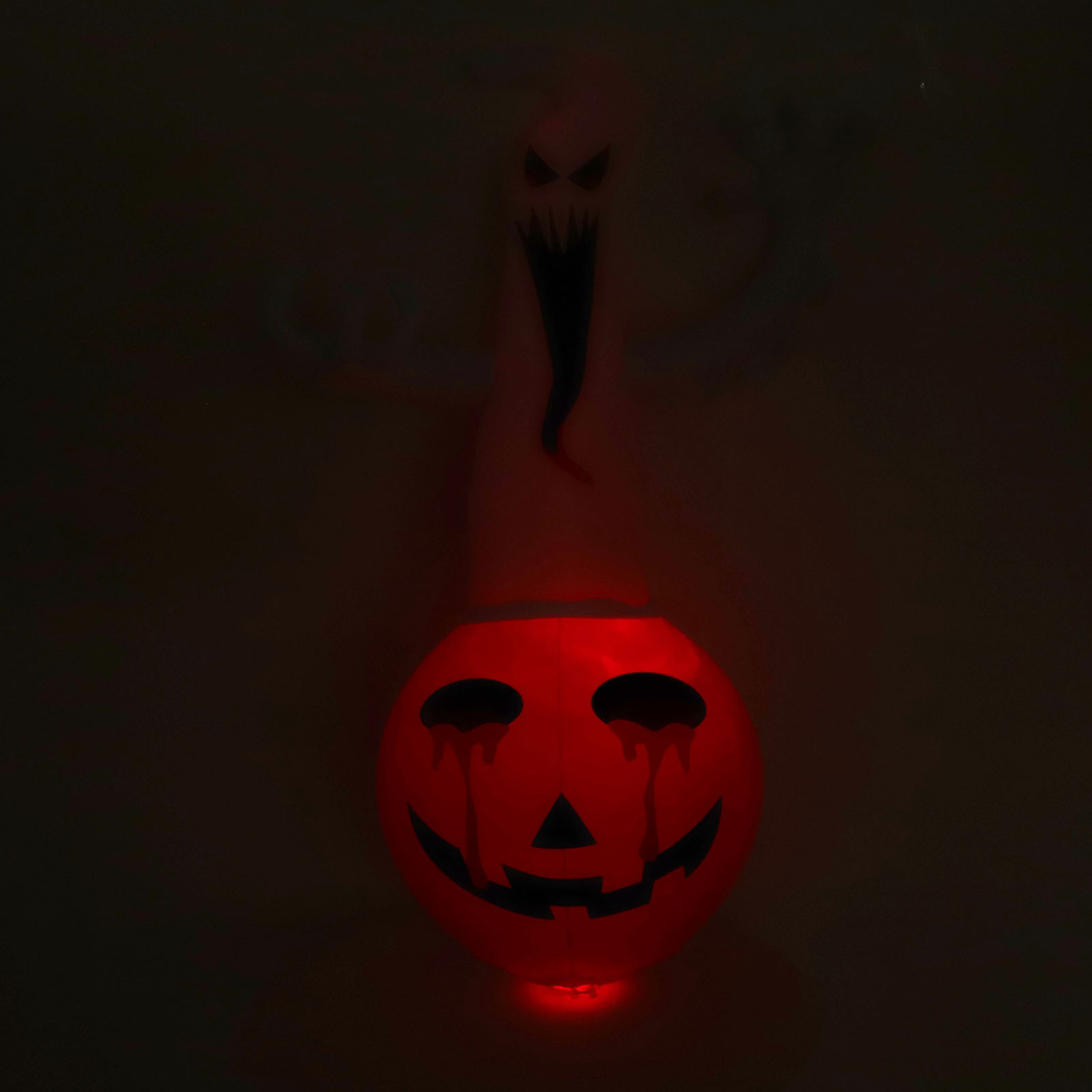 Eine leuchtende Halloween-Dekoration zeigt einen roten Kürbis mit Gesicht und eine Geisterfigur darüber.