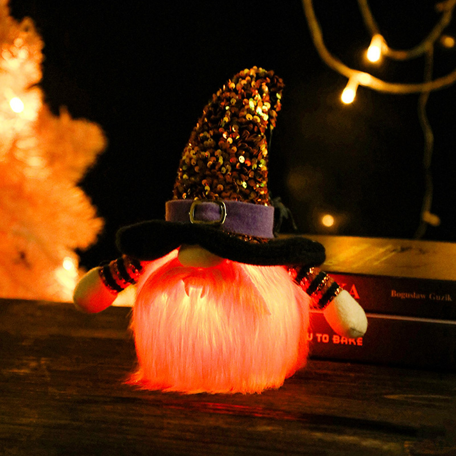 Ein Halloween-Wichtel mit Paillettenhut und leuchtendem orangefarbenem Fell. Er hat einen schwarzen Schnurrbart und gestreifte Ärmel, beleuchtet von Lichterketten.