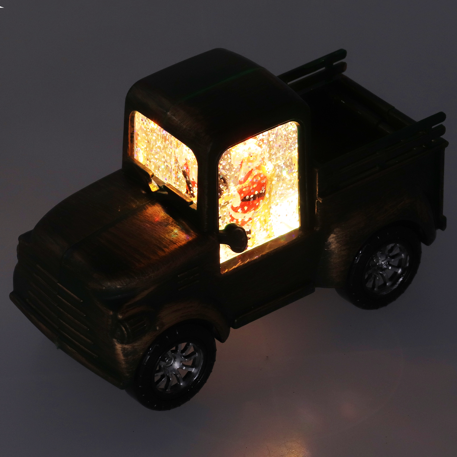 Ein Spielzeug-Lastwagen mit Santa darin. Er ist braun und hat Glitzer in den Fenstern, mit Leuchteffekt.