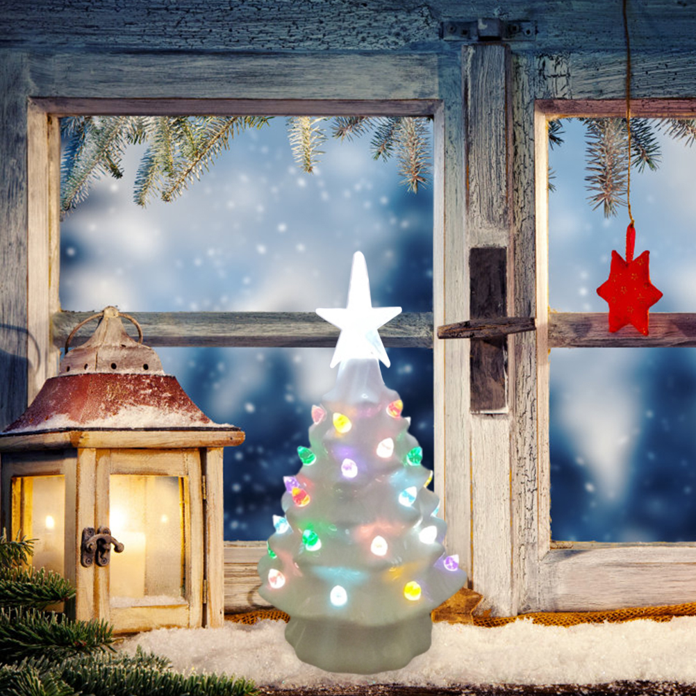 Ein leuchtender Weihnachtsbaum steht am Fenster. Ein roter Stern hängt am Fenster. Draußen schneit es.