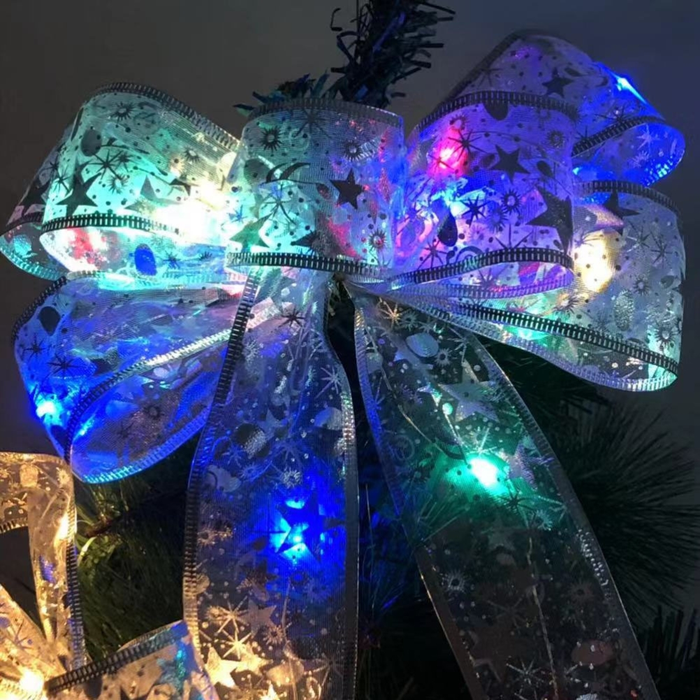 Eine Weihnachtsbaumschleife mit Lichtern. Sie ist silberfarben mit Sternen und Schneeflocken. Die Lichter sind blau, grün und rot.