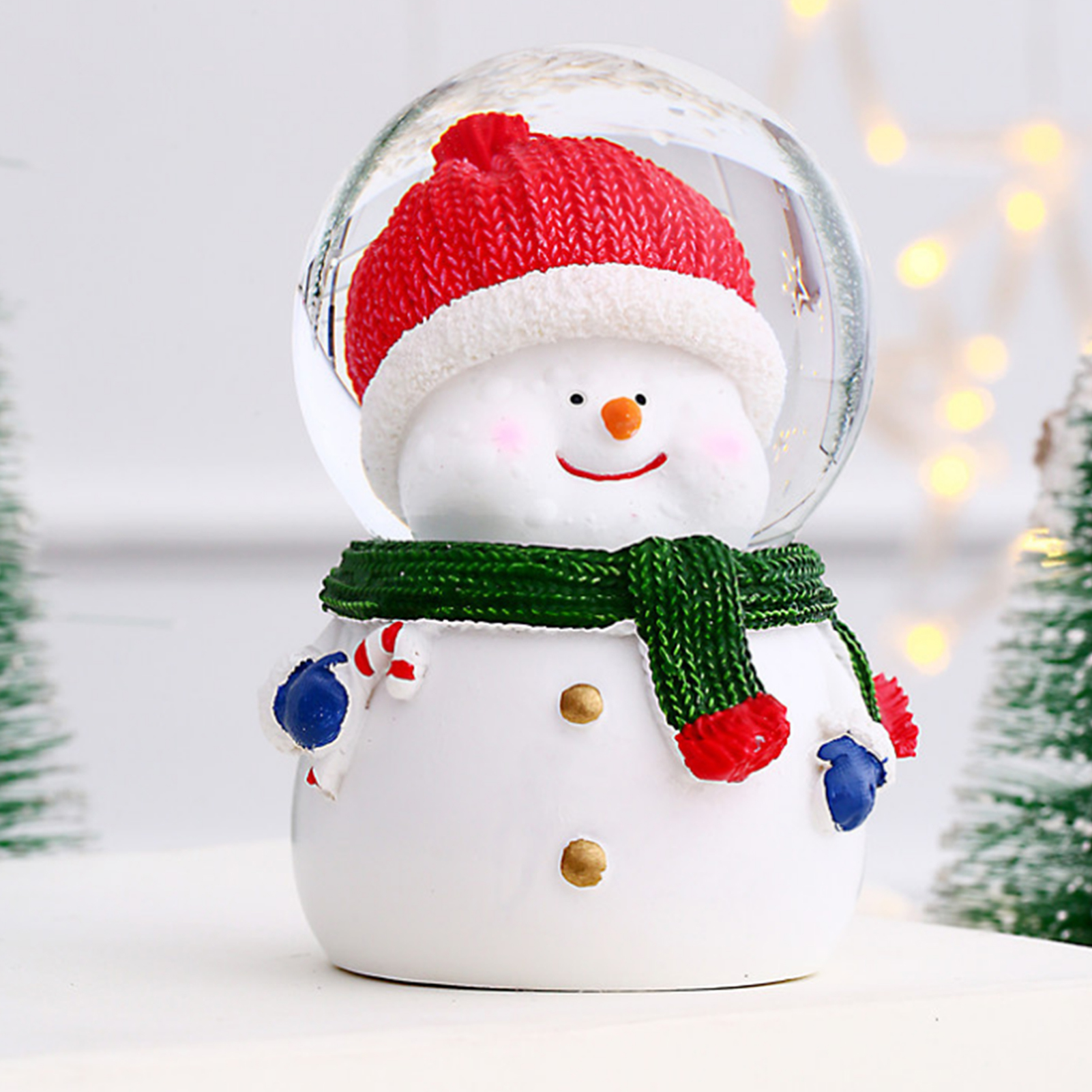 Schneekugel mit einem Schneemann mit roter Mütze, grünem Schal und blauen Fäustlingen. Details zur Zuckerstange.