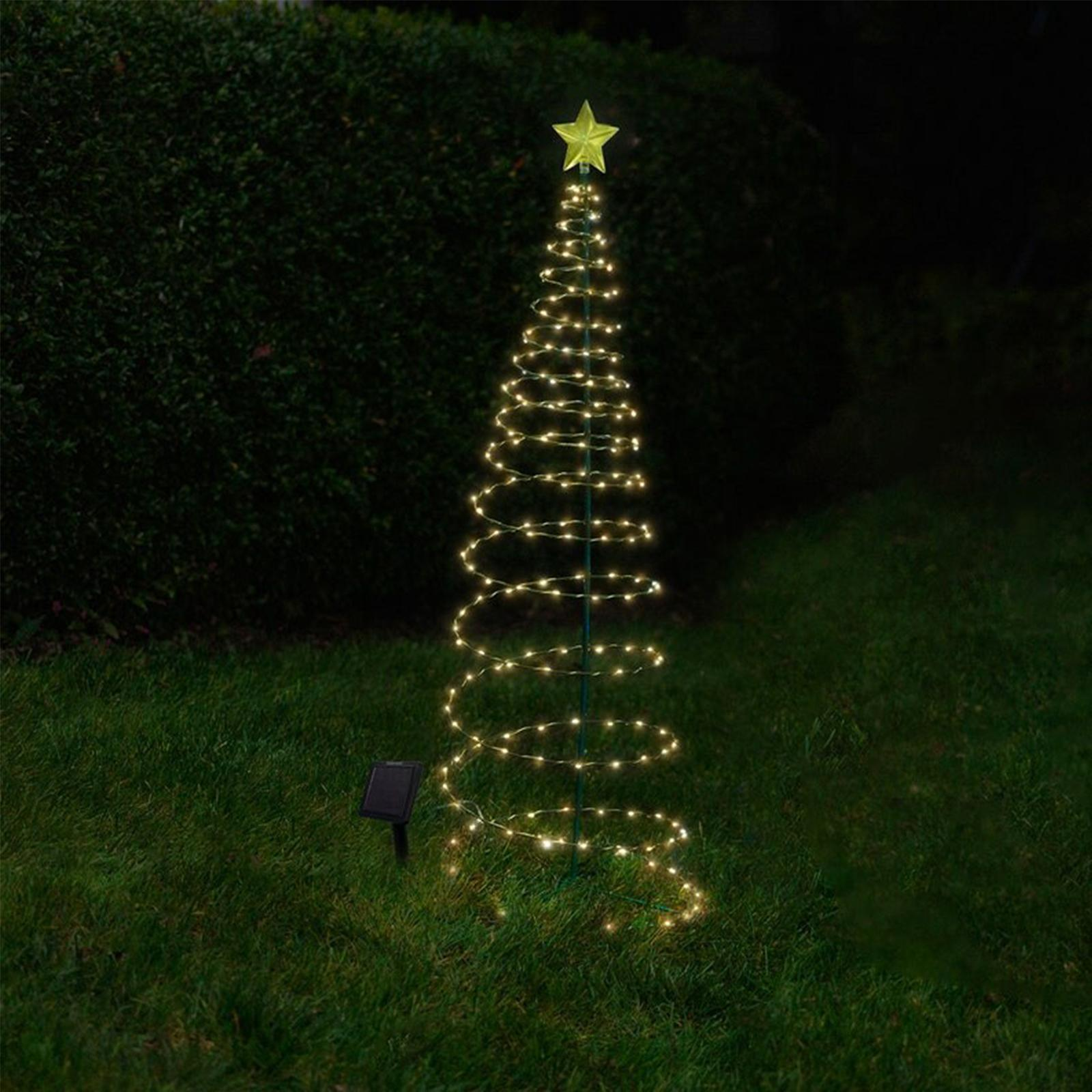 Ein spiralförmiger Weihnachtsbaum aus Lichtern. Oben befindet sich ein gelber Stern. Unten im Gras befindet sich ein Solarpanel.