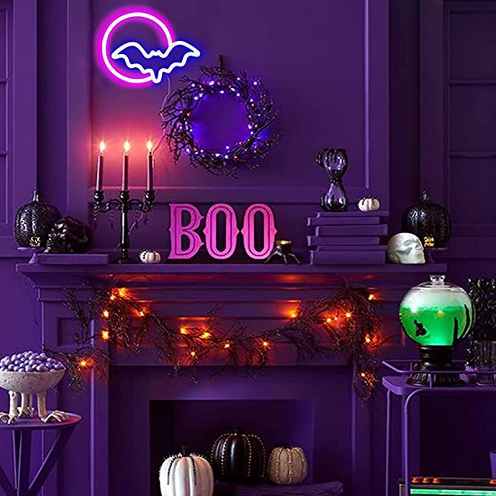 Halloween-Dekoration mit Neon-Fledermausschild, Kerzen, Kürbissen und 'BOO'-Buchstaben. Lila Farbschema mit beleuchteten Girlanden.