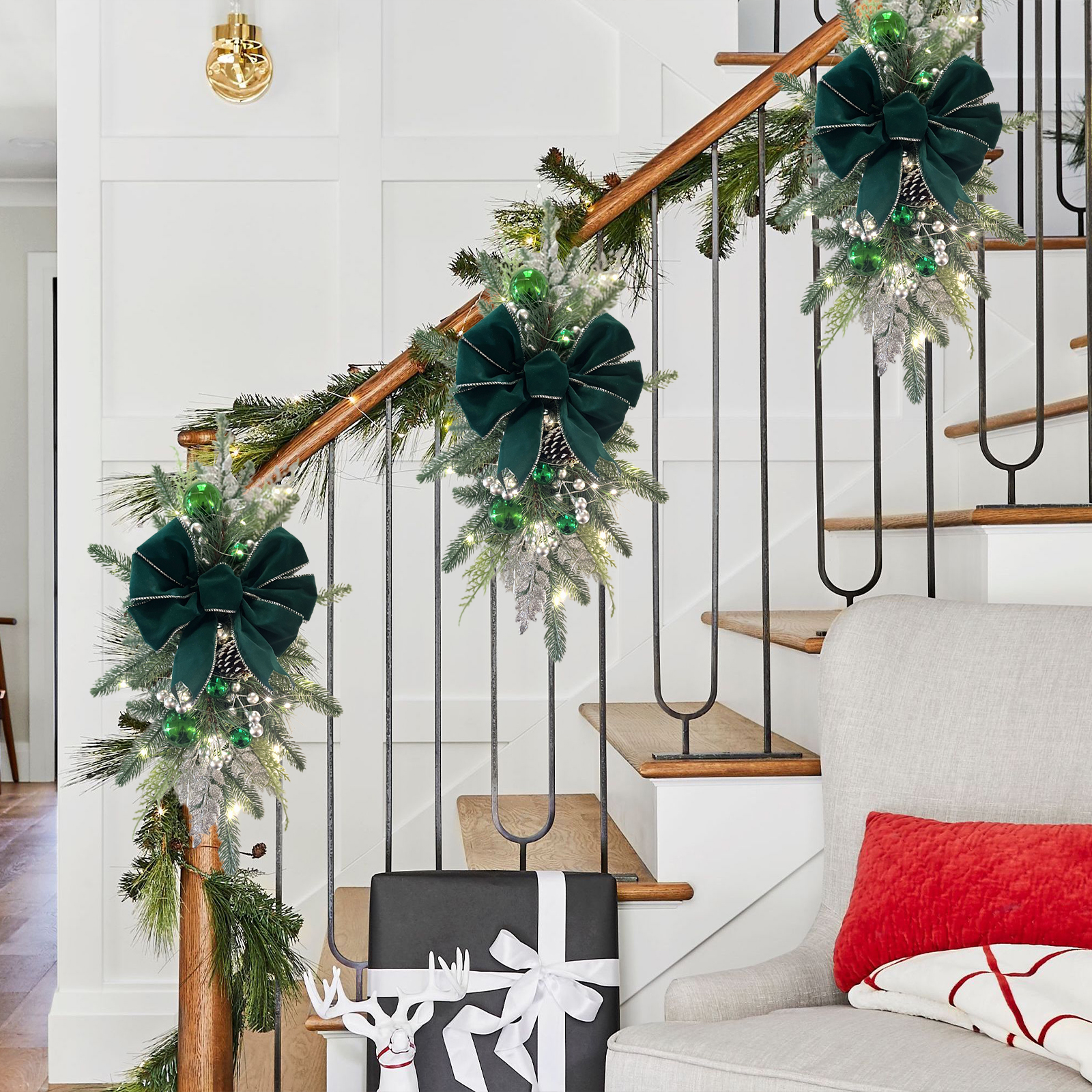 Weihnachtsdekoration mit grünen Schleifen, Girlanden und Geschenken auf der Treppe. Ein Stuhl mit rotem Kissen steht daneben. Eine goldene Wandlampe ist sichtbar.