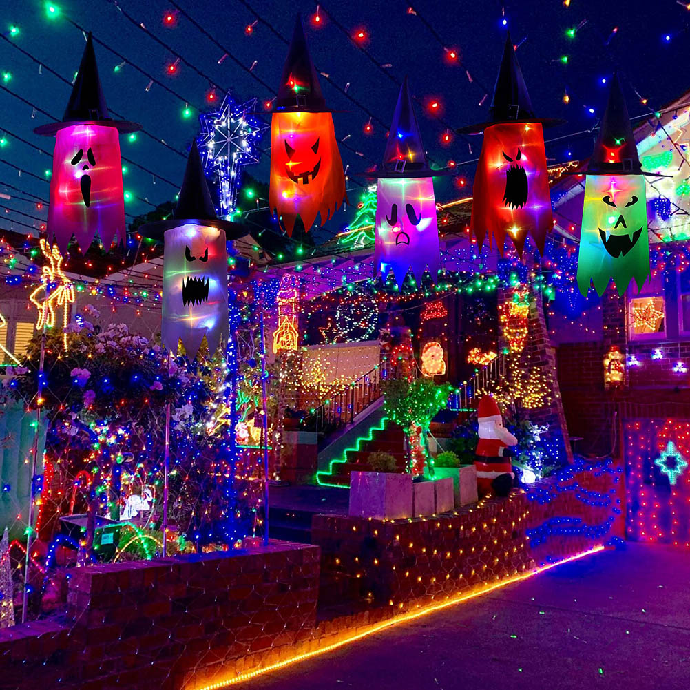 Halloween-Dekorationen mit Hexenhüten und beleuchteten Geistern, Haus mit Weihnachtsbeleuchtung und Weihnachtsmann geschmückt.
