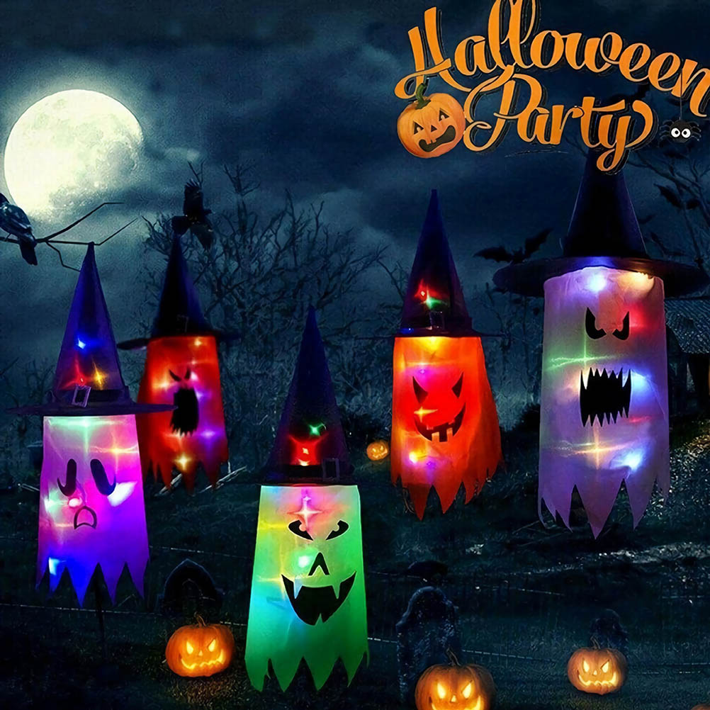 Halloween-Dekorationen mit Hexenhüten und leuchtenden Gesichtern. Kürbisse und ein Vollmond sind sichtbar. Der Hintergrund zeigt einen unheimlichen Wald.