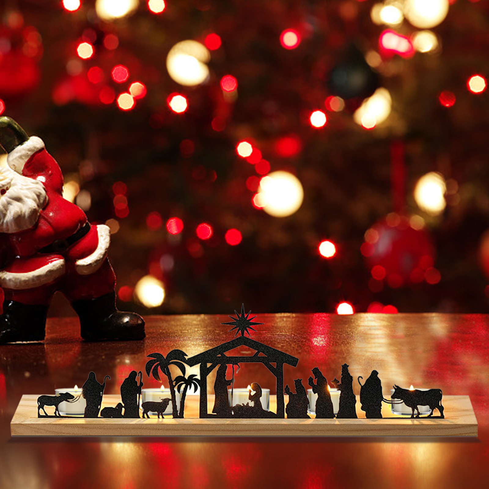 Eine Weihnachtskrippe mit Silhouetten. Links eine Santa-Figur. Rote und weiße Lichter im Hintergrund.