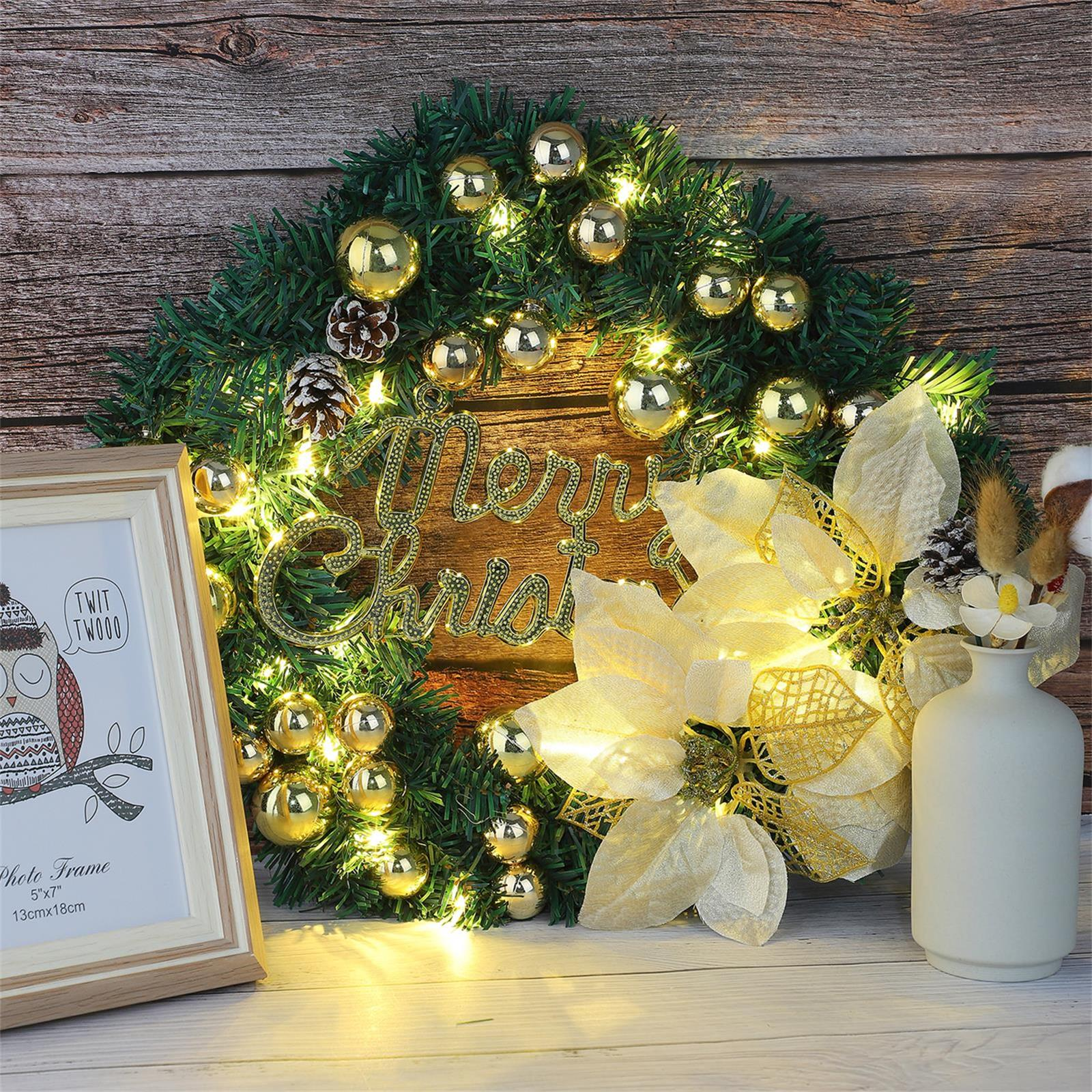 Weihnachtskranz mit goldenen Ornamenten, Lichtern und einem Fotorahmen auf einem hölzernen Hintergrund. Eine Vase mit Blumen rechts.