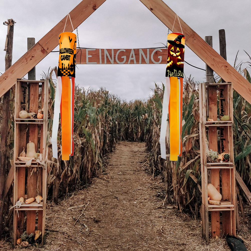 Eingang zu einem Maislabyrinth, für Halloween dekoriert. Holzkisten mit Kürbissen säumen den Weg. Schilder und Windspiele ergänzen das Thema.