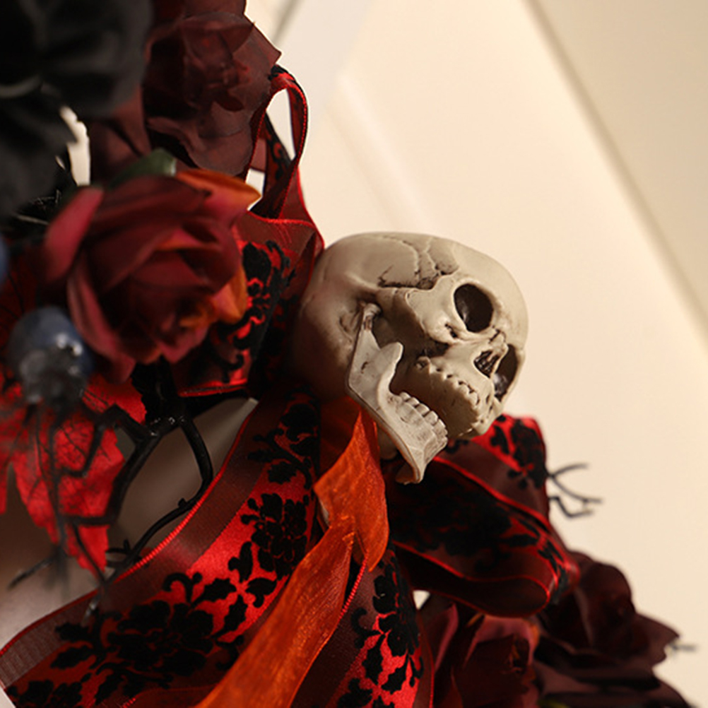 Eine Halloween-Dekoration mit einem Totenkopf, roten Rosen und gemusterten Bändern. Der Hintergrund ist eine hellbeige Wand.