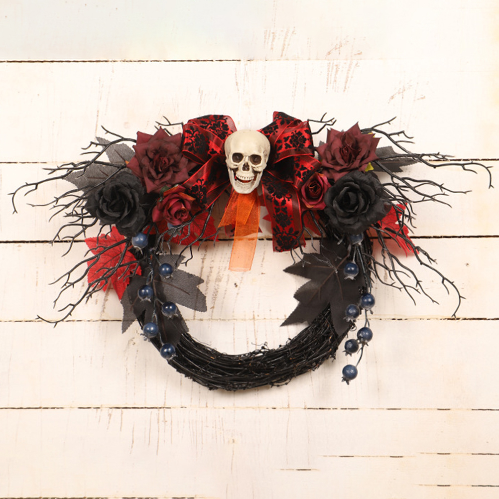 Halloween-Kranz mit Totenkopf, roten Rosen, schwarzen Blättern und Beeren. Vor weißem Holzgrund.