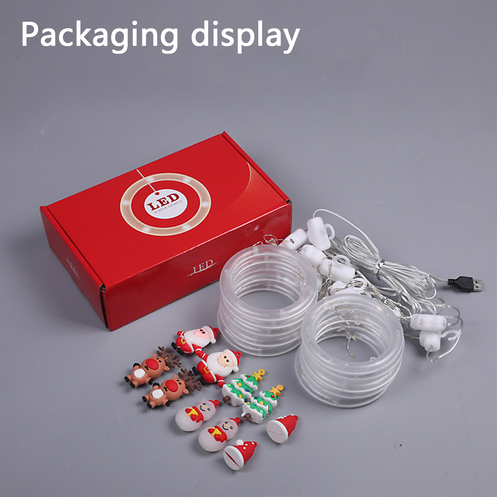 Verpackungsanzeige mit Weihnachtsdekorationen, LED-Leuchten und einer roten Box. Der Hintergrund ist grau.